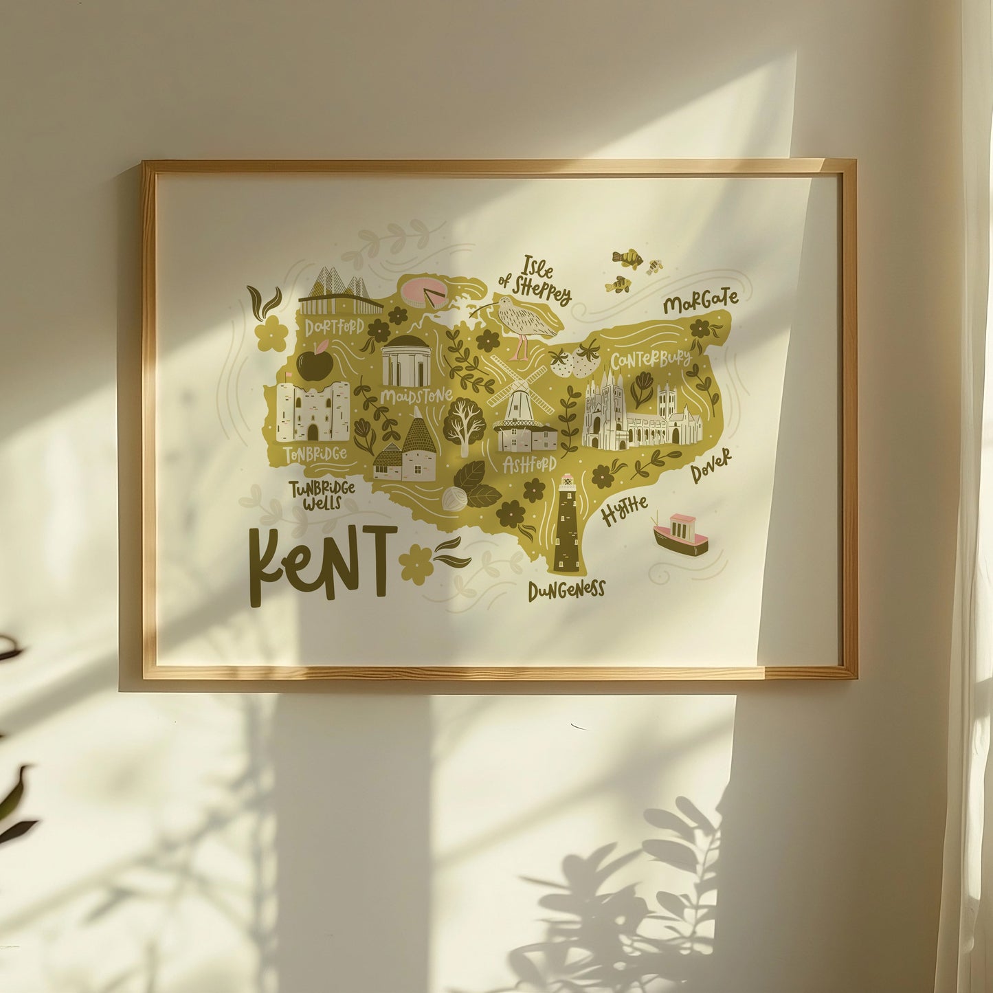 Lifestyle photo of an illustrated map of Kent, showing a framed print with a window shadow.