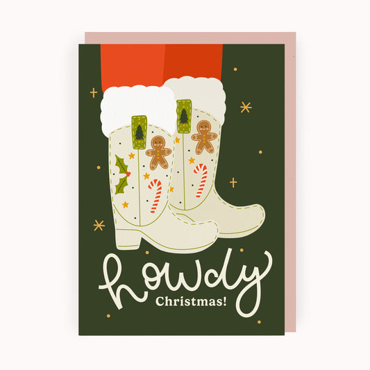 Christmas card with illustrated festive cowboy boots, decorated with gingerbread men, and candy canes on a green background.